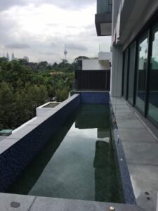 Front view of a luxurious 5-storey bungalow in Bukit Tunku, featuring modern architectural design, a private swimming pool with city views, and surrounded by lush greenery