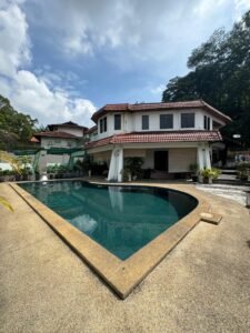 Front view of a luxurious bungalow in Bukit Damansara, featuring a mature landscaped garden and elegant architectural design.